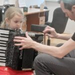 Dziewczynka próbuje grać na harmonii