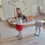Dziewczynki próbują grać na harmonii
