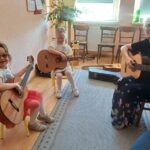 Dziewczynki pod okiem nauczycielki Szkoły Muzycznej uczą się pierwszych akordów granych na gitarze