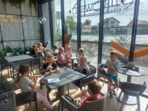 dzieci siedzą przy stolikach w kawiarni Mini Brejk, i jedzą lody