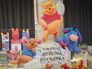 półka z książkami o Kubusiu Puchatku oraz pluszowa postać misia
