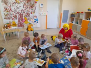 dzieci z grupy Promyczki oglądają książki o Kubusiu Puchatku przyniesione przez panią Asię z biblioteki