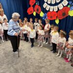 Zdjęcie przedstawia Seniorkę śpiewającą dzieciom.