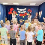 Zdjęcie przestawia Panie w strojach ludowych i śpiewające dzieci.