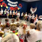 Zdjęcie przedstawia dzieci w strojach ludowych podczas występu.