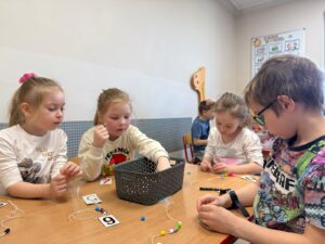 Starszaki rozwiązują zadania matematyczne - nawlekają koraliki